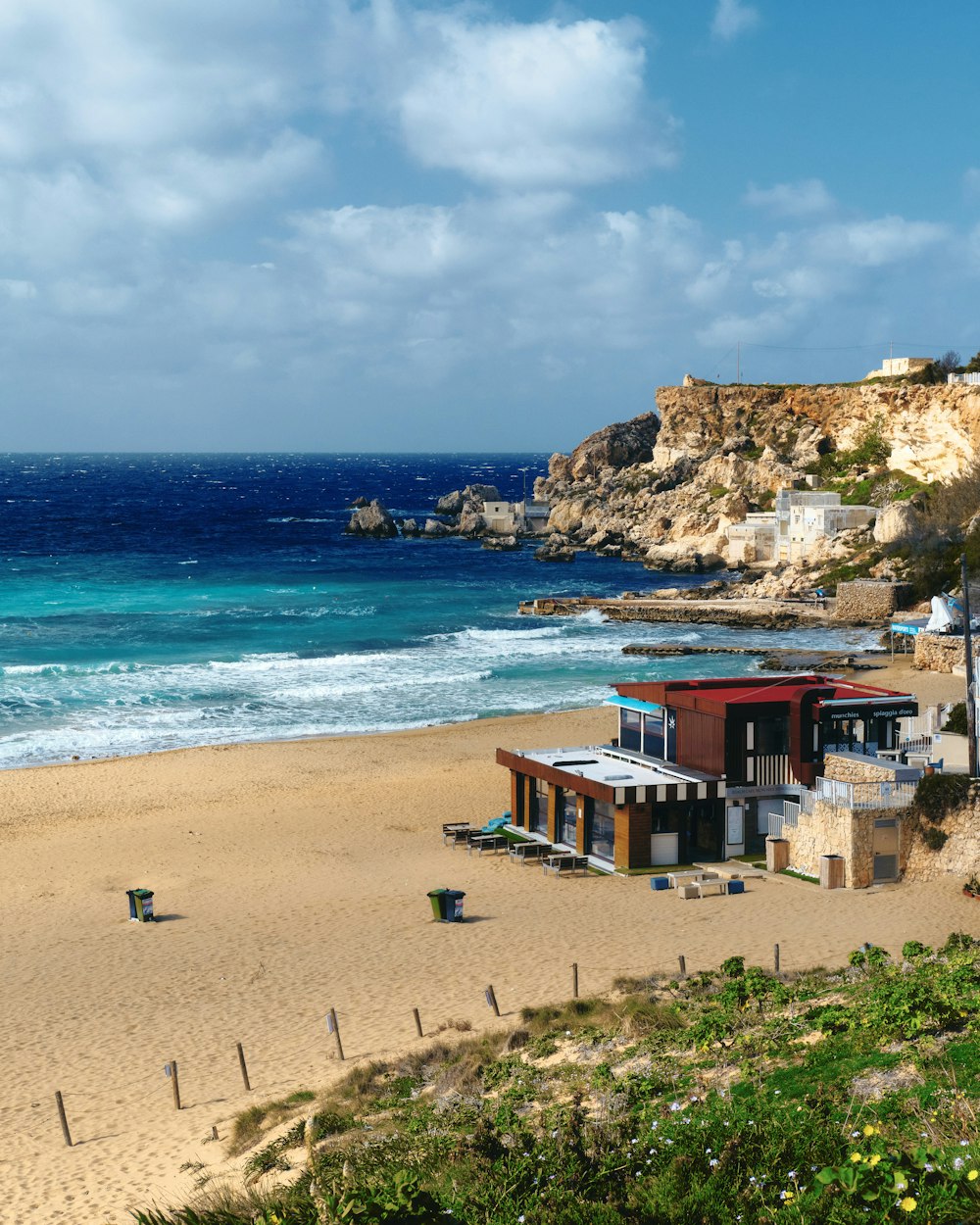 a beach with a house on the sand next to the ocean