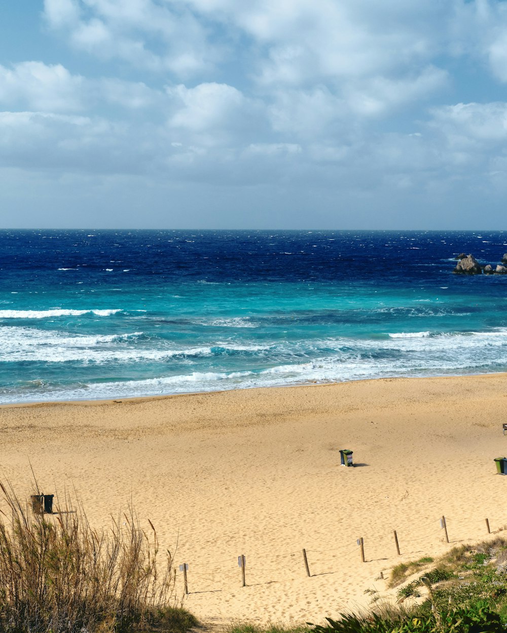 a sandy beach next to the ocean under a cloudy sky