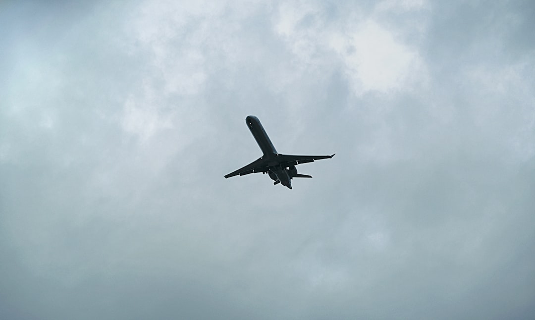 a large jetliner flying through a cloudy sky, Ground view of airplane flying overhead.