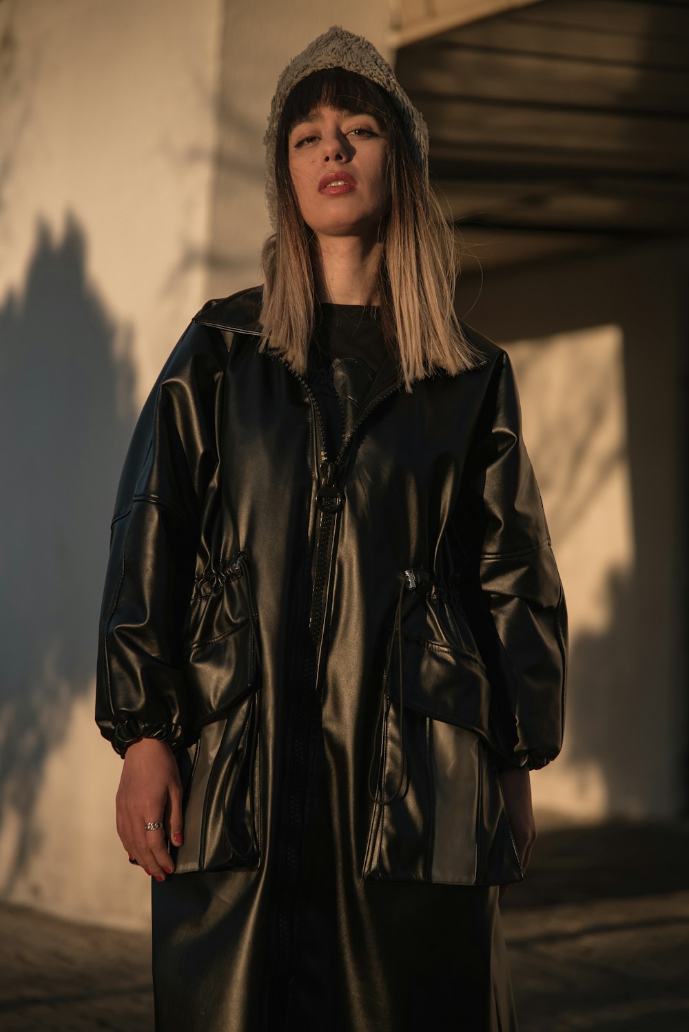 a woman wearing a black leather coat and hat