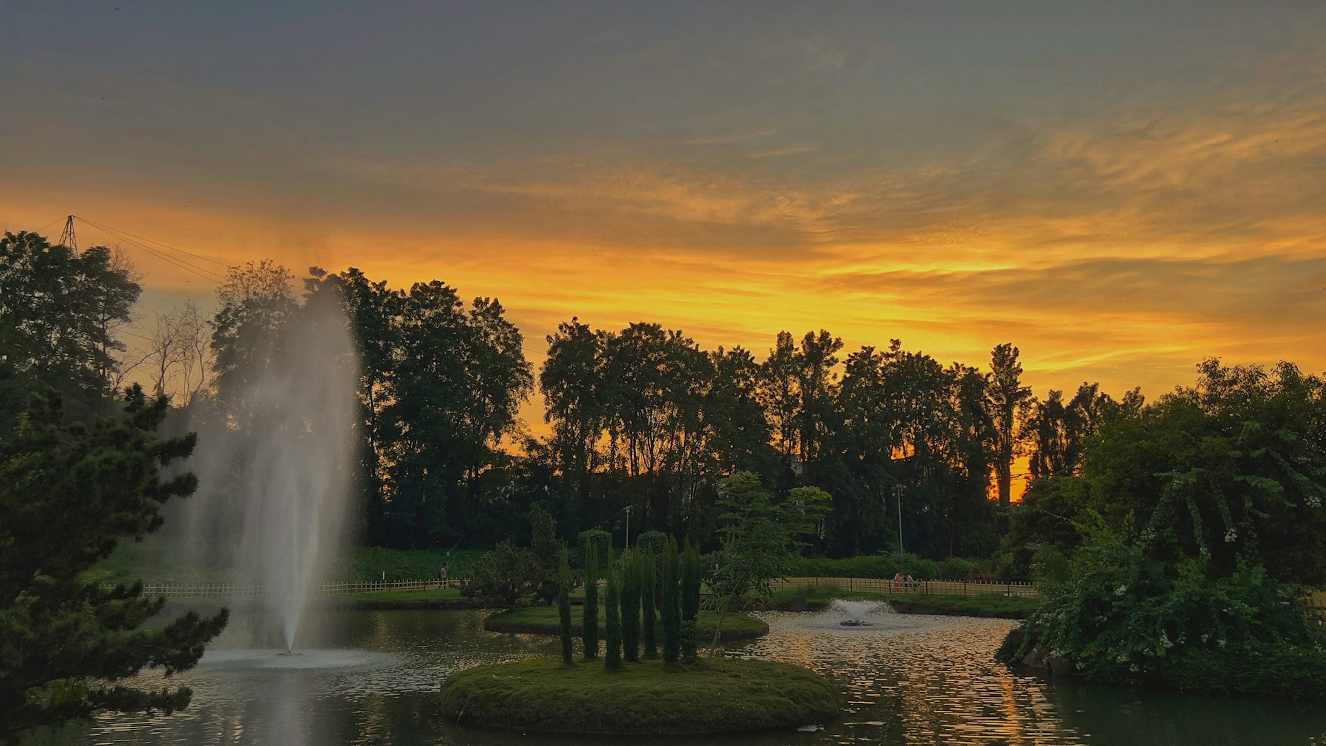Sunset view over the peaceful garden area with blooming flowers and a reflective pond, perfect for luxury celebrations.