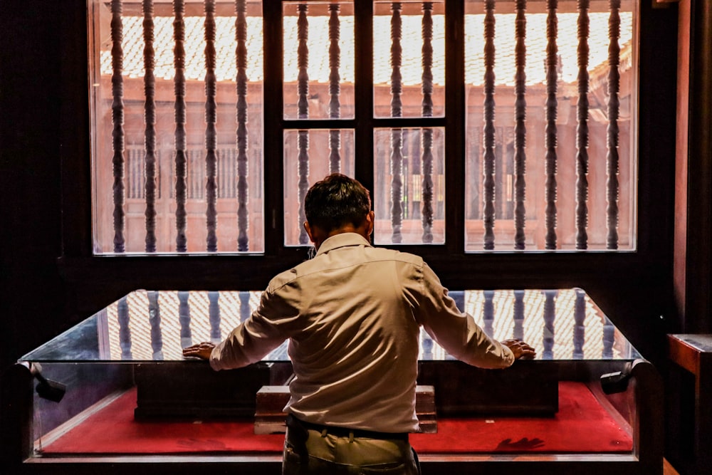 a man standing in front of a window looking out