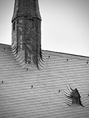 a black and white photo of a roof with a clock tower