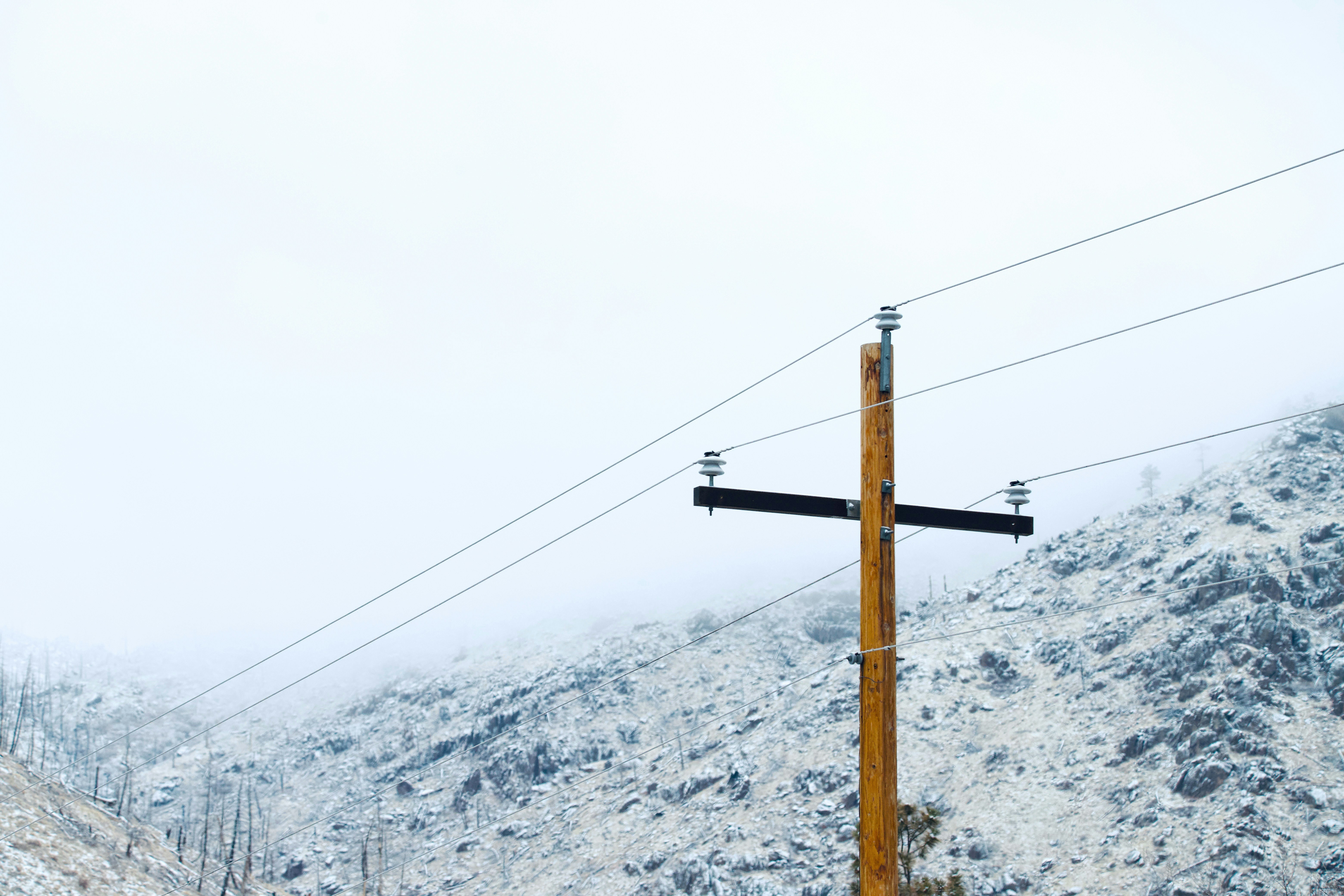 a telephone pole in the middle of a snowy mountain
