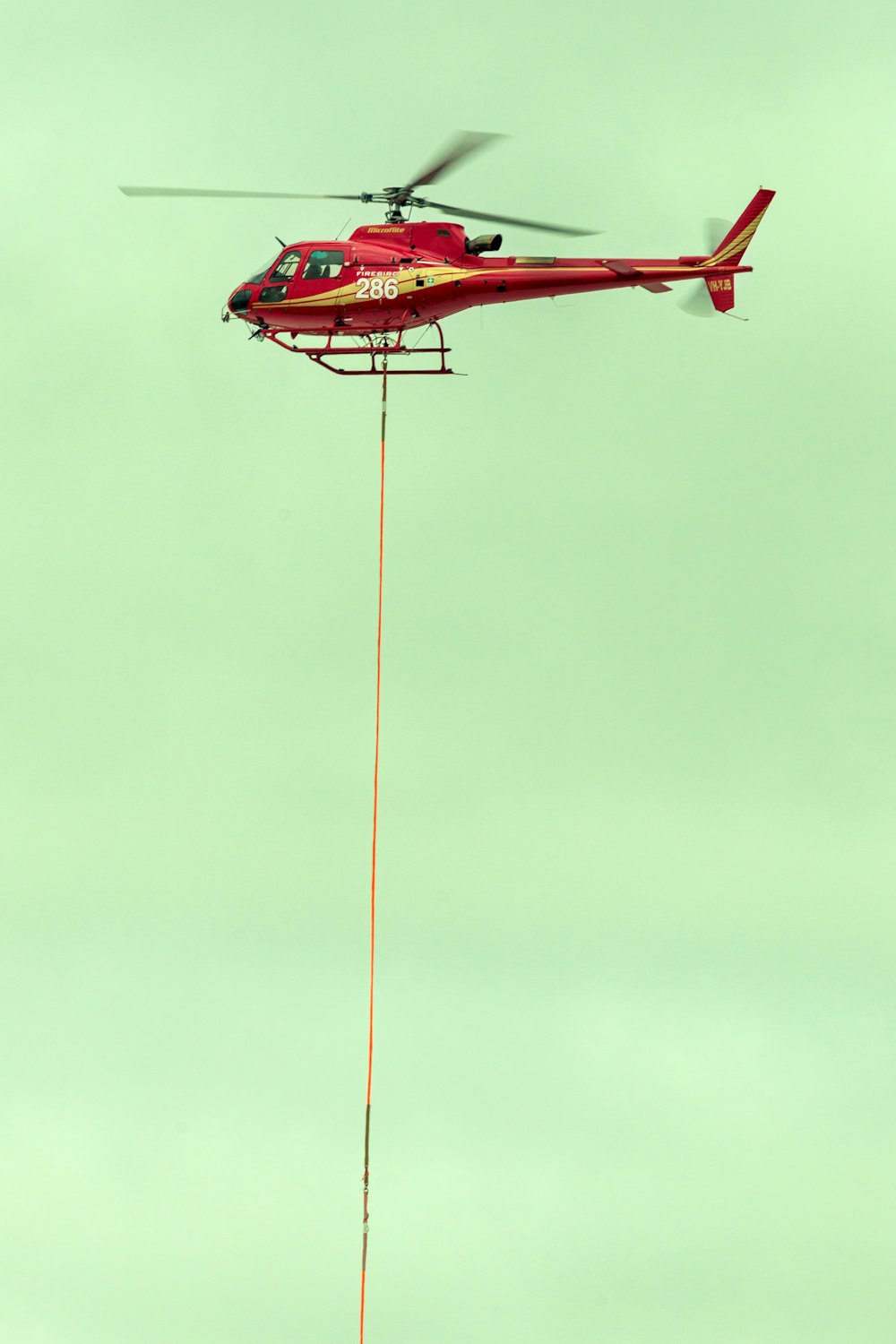 a red helicopter with a rope attached to it