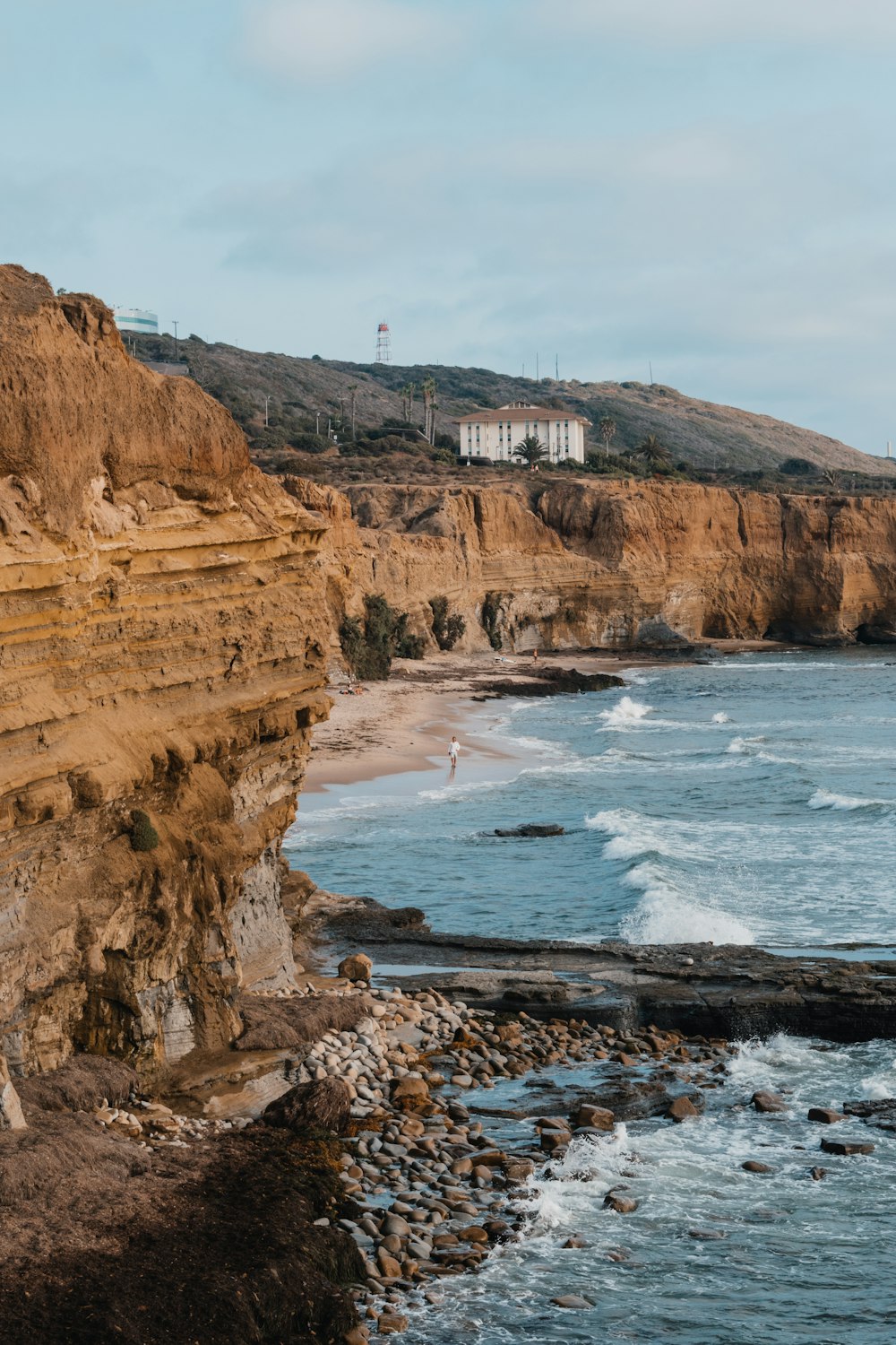 a rocky cliff overlooks the ocean and beach