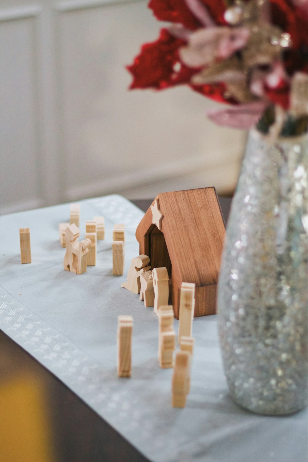 a small wooden house next to a vase of flowers