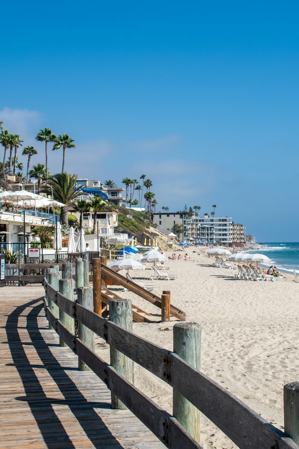 a wooden walkway leading to a beach with palm trees