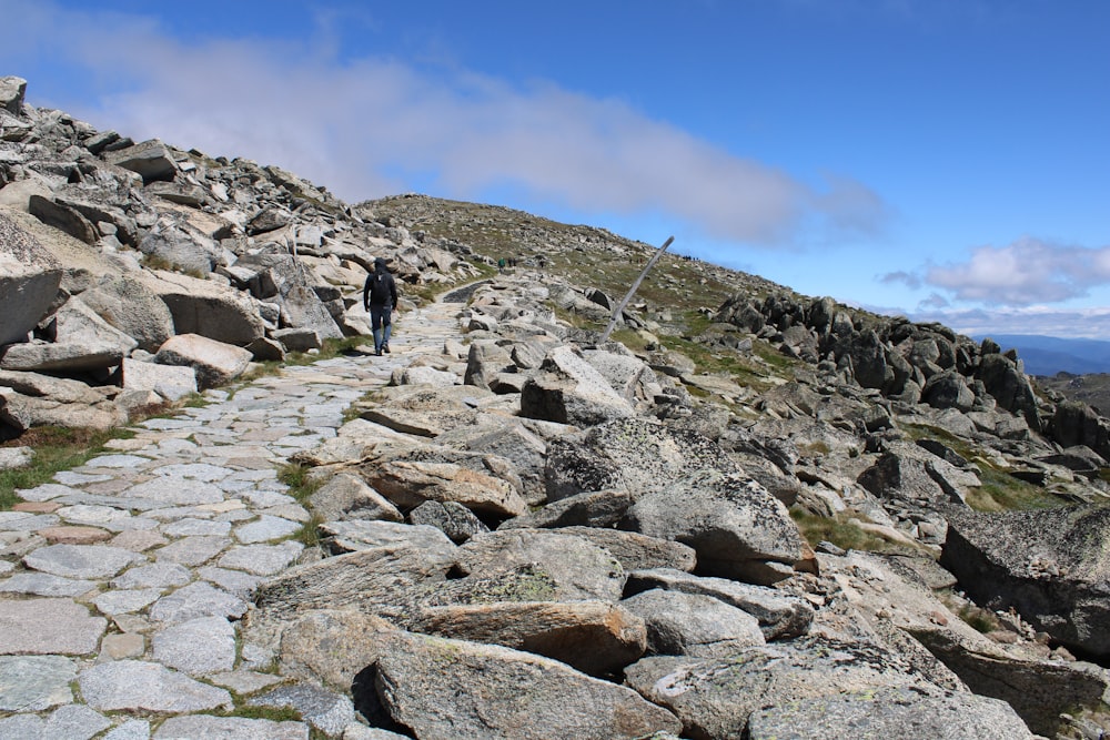 a man walking up a rocky path in the mountains