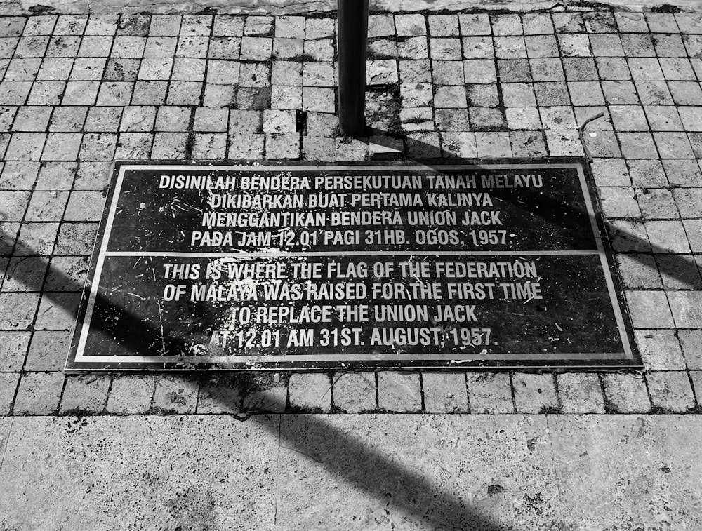 a black and white photo of a plaque on a sidewalk
