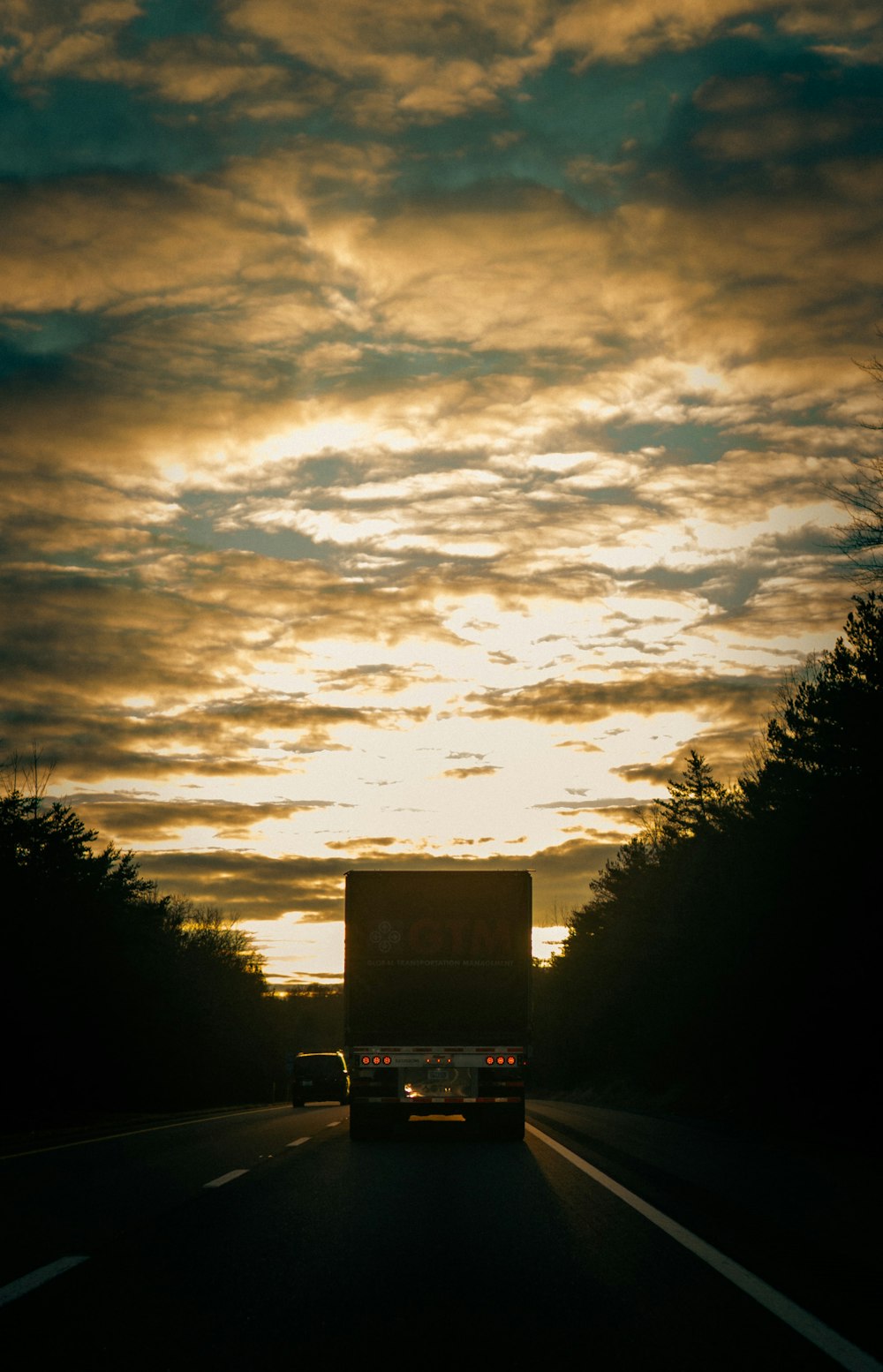 a truck driving down a road under a cloudy sky