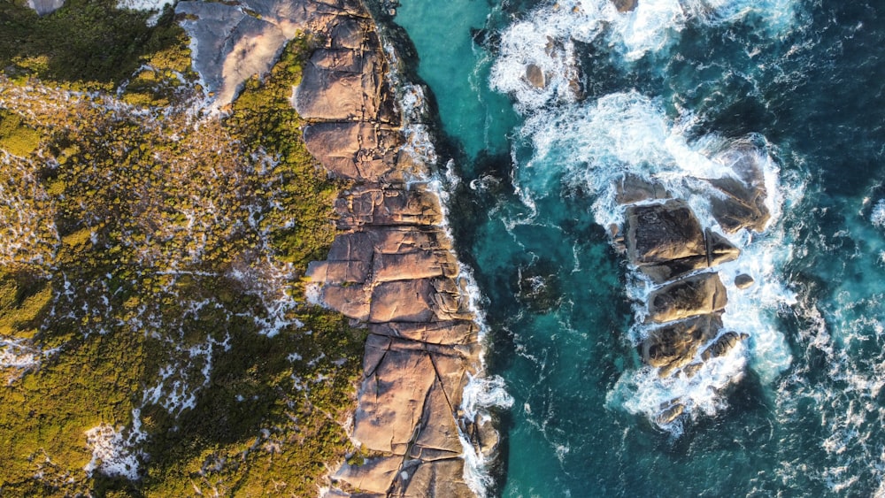 an aerial view of the ocean and rocks