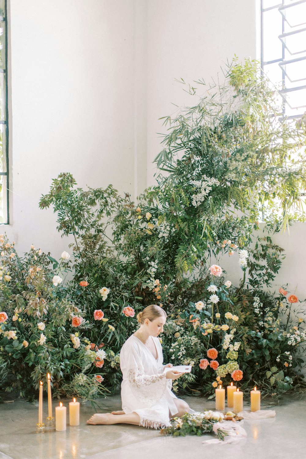 a woman sitting on the ground in front of flowers and candles