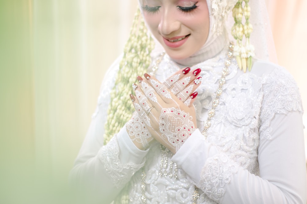 a woman in a white wedding dress holding her hands together