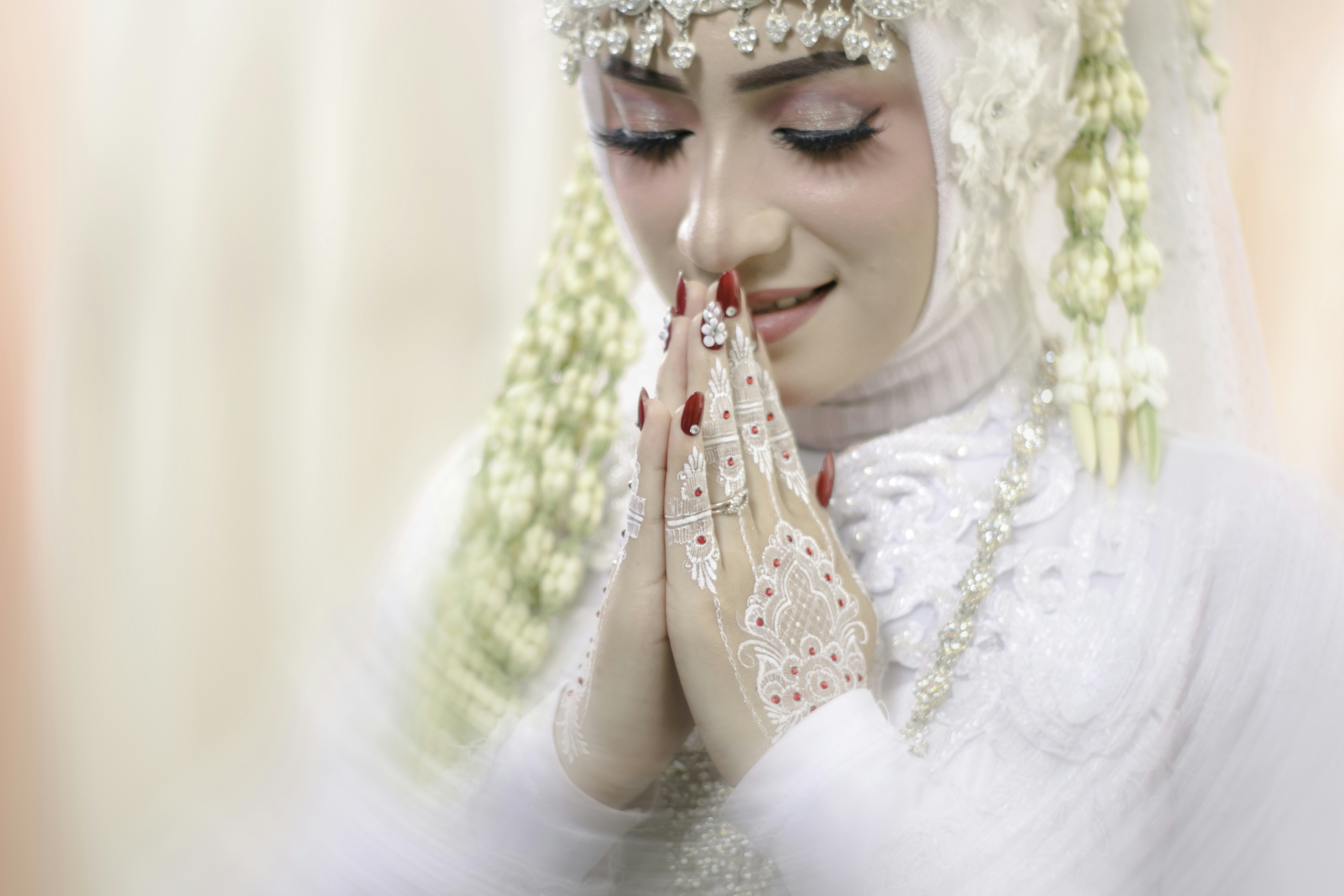 a woman in a white wedding dress holding her hands together