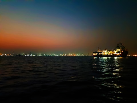 A sleek cargo ship loaded with raw materials against a twilight sky, symbolizing global trade.