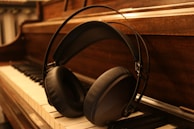 A pair of well-worn headphones resting on a piano keyboard under low, moody lighting.