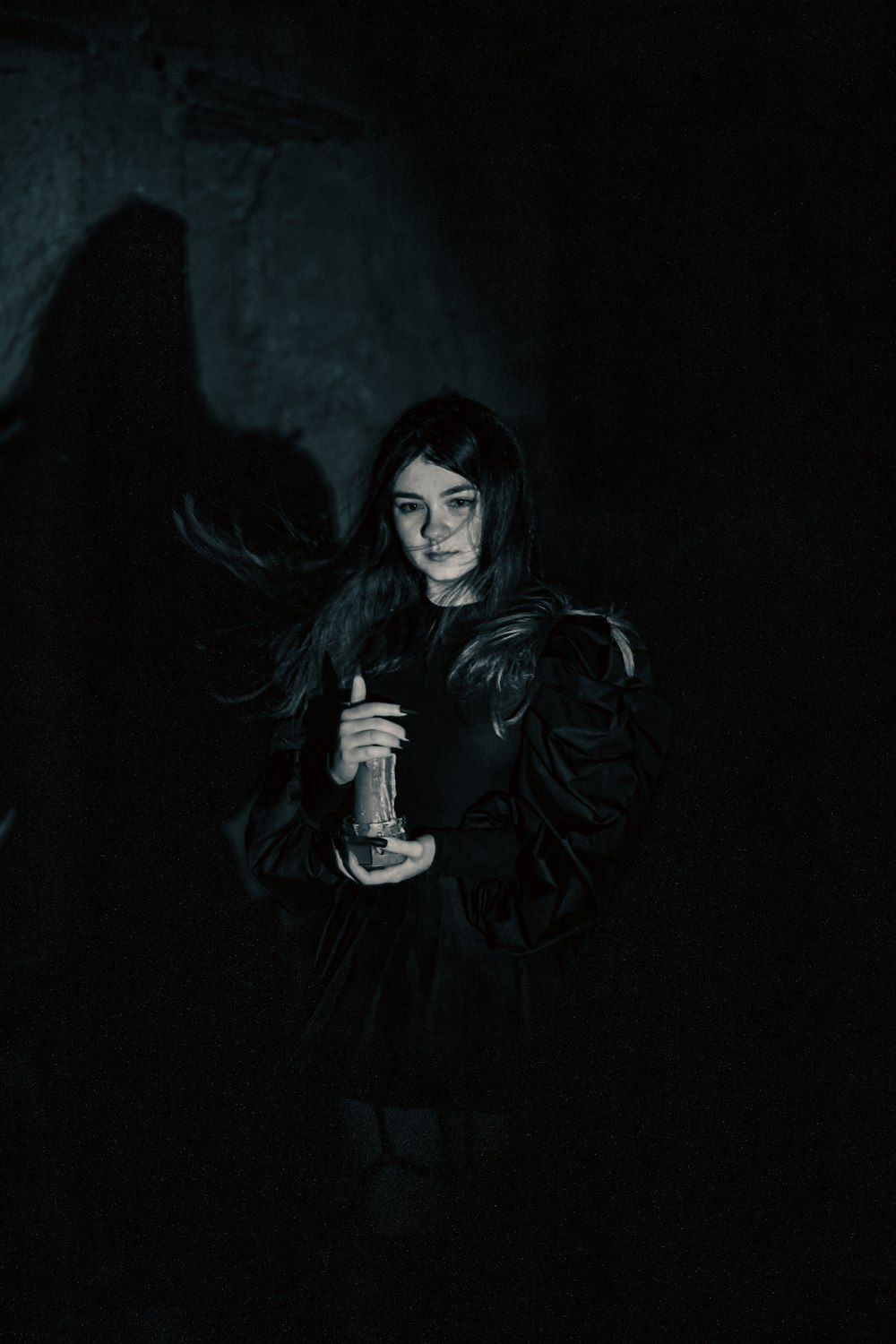 a woman standing in the dark holding a bottle