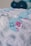Gift bags decorated with a paisley pattern and a tag featuring a cartoon pink shark, with the words 'Thanks Baby Shark Party'. Blue and white balloons are blurred in the background.