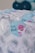 Gift bags decorated with a paisley pattern and a tag featuring a cartoon pink shark, with the words 'Thanks Baby Shark Party'. Blue and white balloons are blurred in the background.