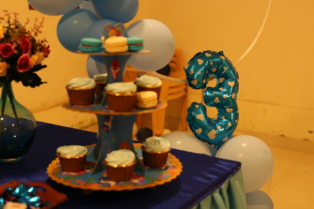 a blue table topped with cupcakes and balloons