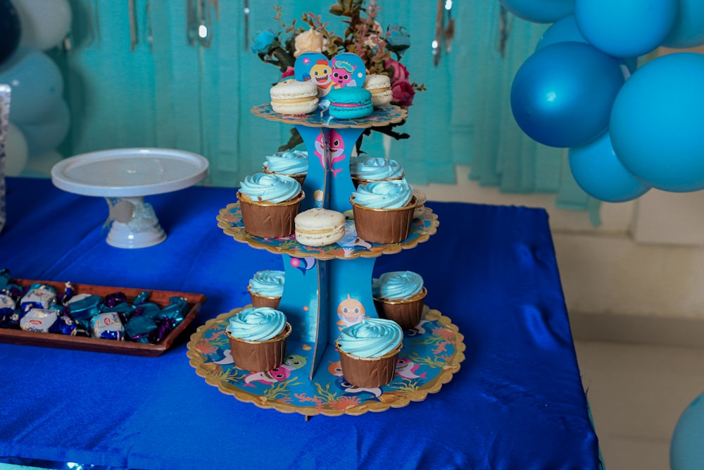 a blue table topped with lots of cupcakes