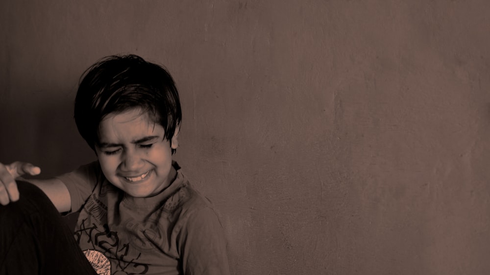 a young boy sitting on the floor smiling