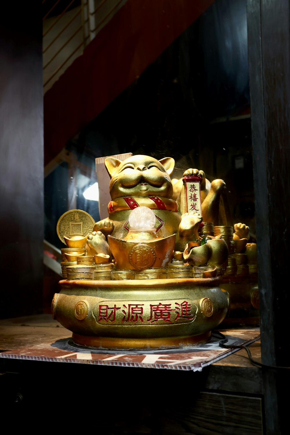 a golden statue of a cat with a bowl of food