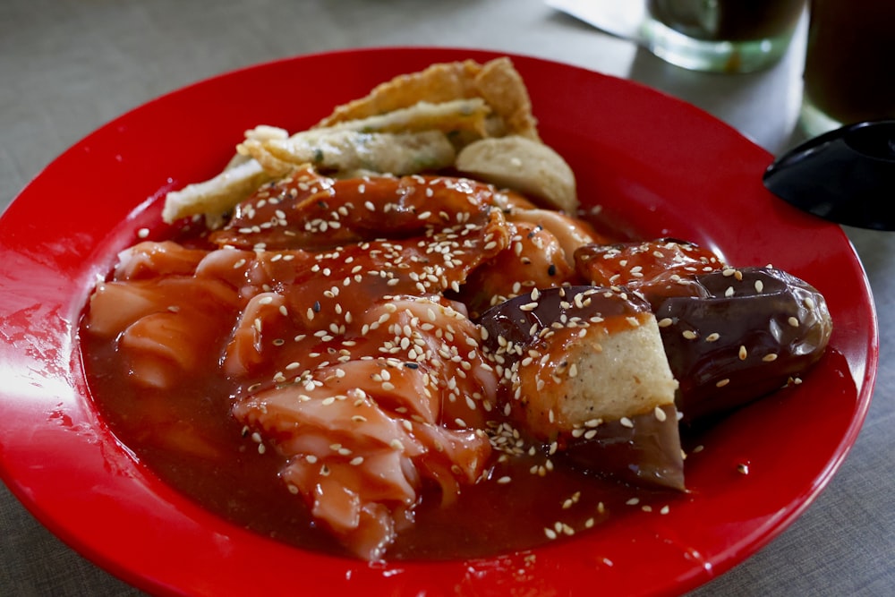 a red plate topped with meat covered in sauce