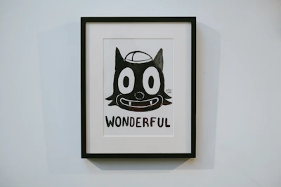 A framed poster featuring a whimsical black-and-white character set against a bright, colorful backdrop.