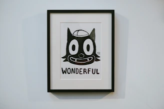 A framed poster featuring a whimsical black-and-white character set against a bright, colorful backdrop.