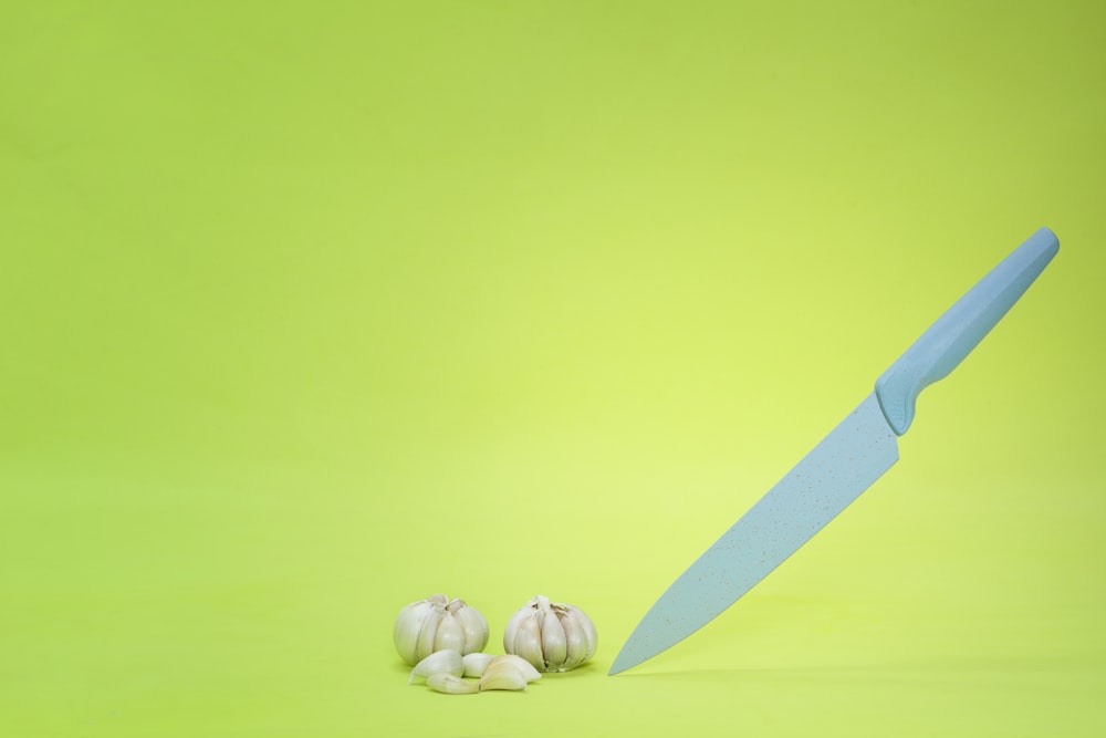a knife and some garlic on a green background