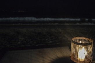 Handcrafted ocean-themed candles glowing softly on a sandy beach at sunset