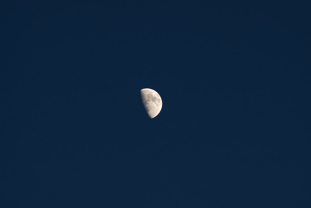 a half moon is seen in a clear blue sky