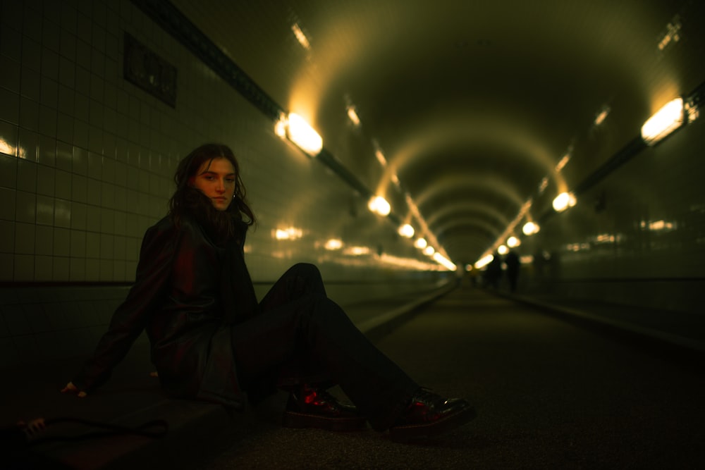 a woman sitting on the ground in a tunnel