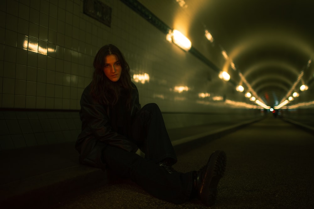 a woman sitting on the ground in a tunnel