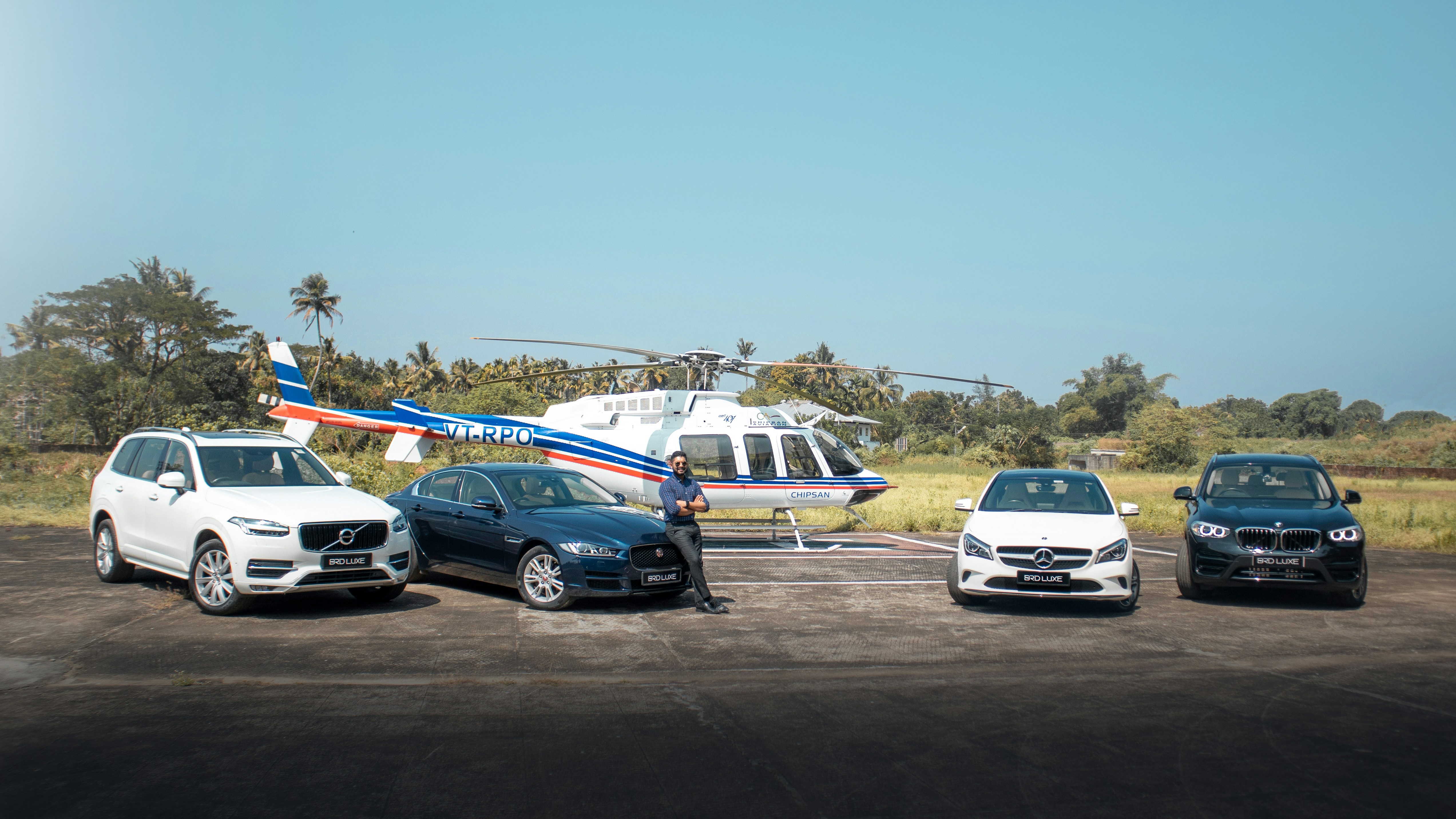 three cars are parked in front of a helicopter