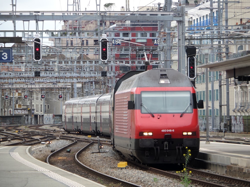 Ein roter und silberner Zug, der über Bahngleise fährt
