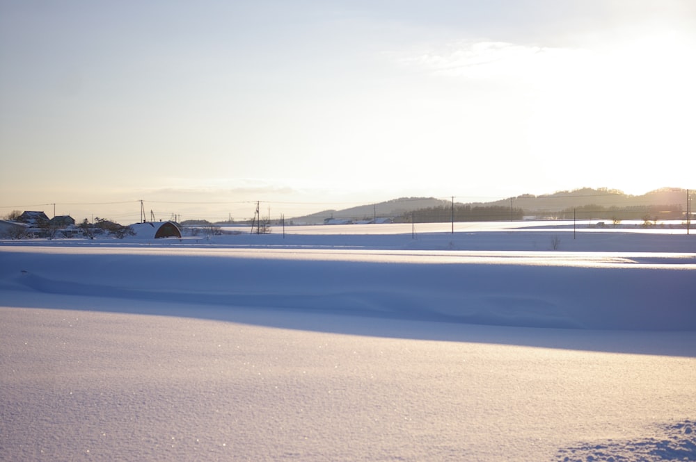 the sun is shining on a snowy field