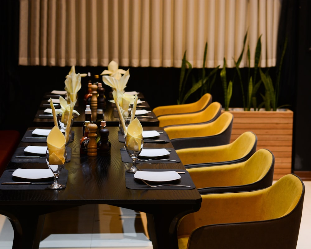 a long table with yellow chairs and black table cloths