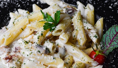 a plate of pasta with parmesan cheese and a cherry