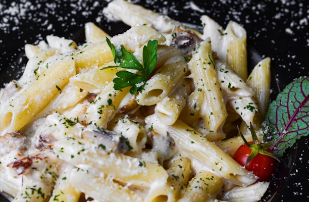 a plate of pasta with parmesan cheese and a cherry