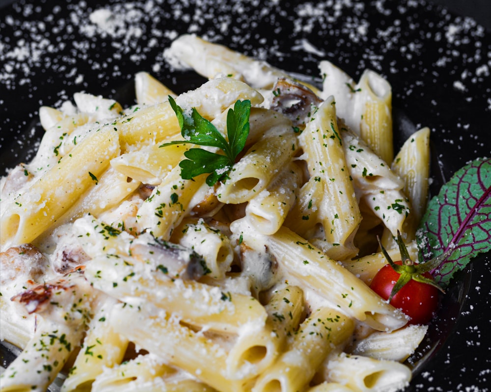 a plate of pasta with parmesan cheese and a cherry