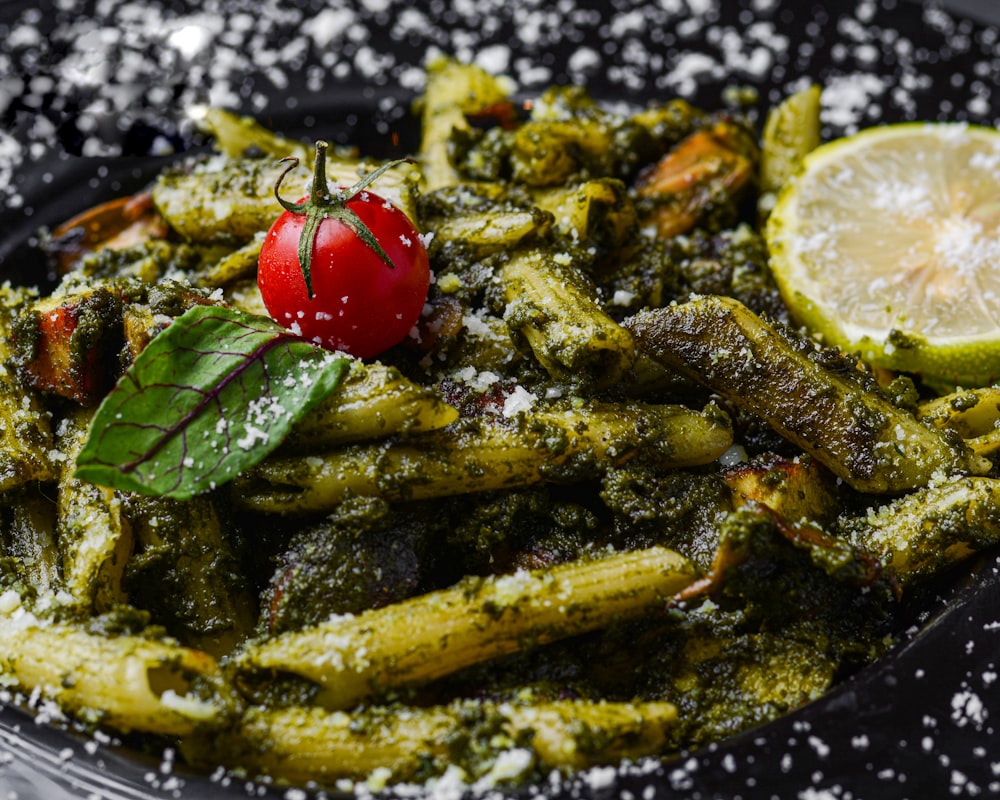 a plate of pasta with pesto and a cherry