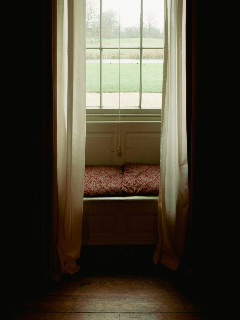 a window with curtains and a bench in front of it