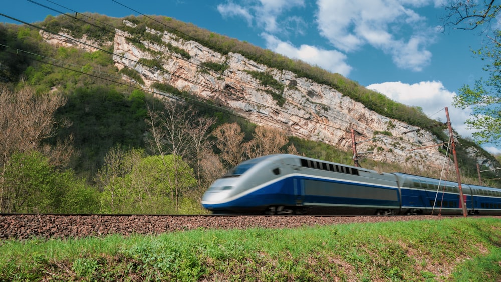 Un tren azul y blanco que viaja por las vías del tren