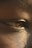 An extreme close-up of a person's eye, highlighting the texture of the skin around it and the details in the reflection on the eye surface. The lighting provides a warm tone, emphasizing the intricate details of the skin and eye.