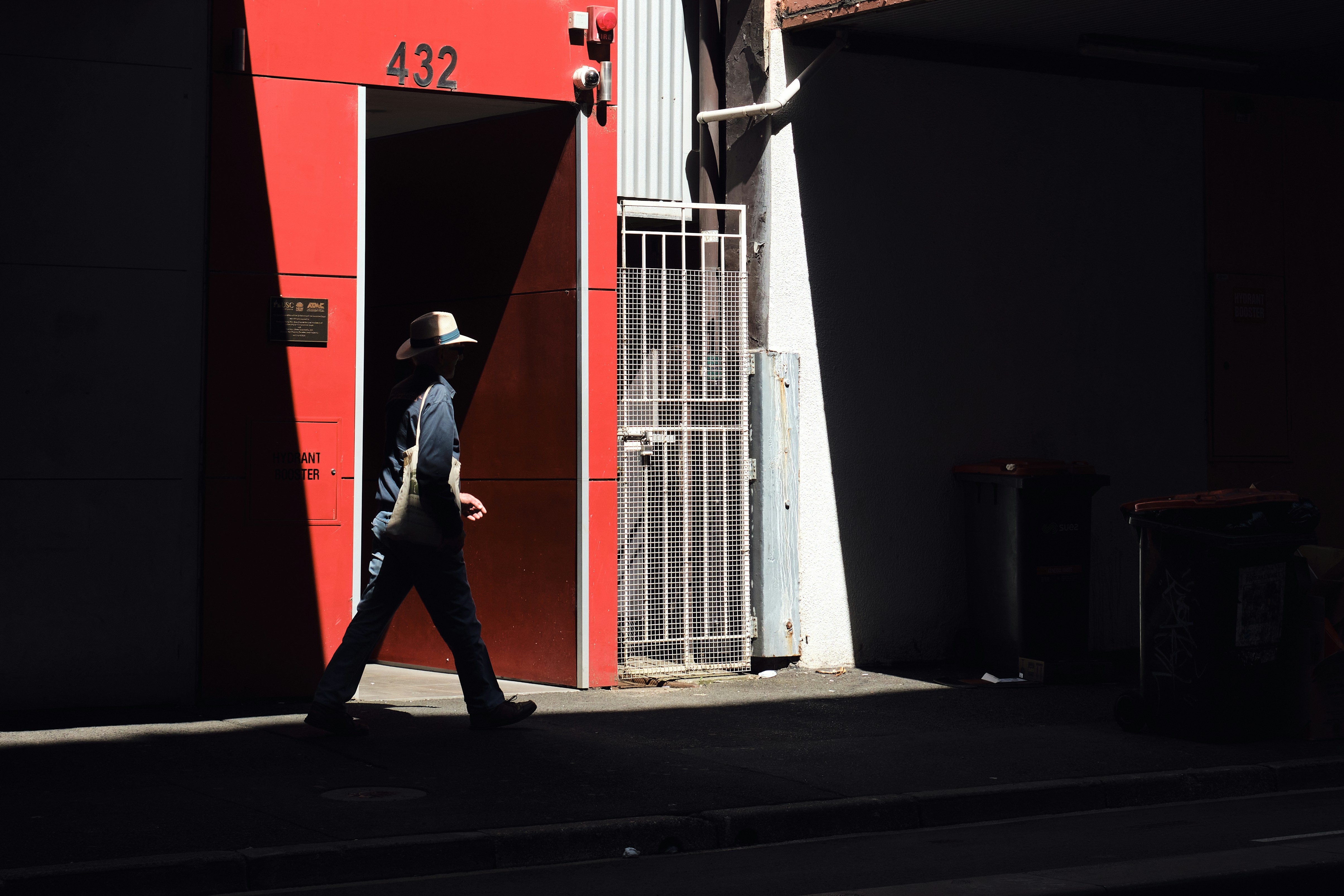 A man walking down a street past a red building