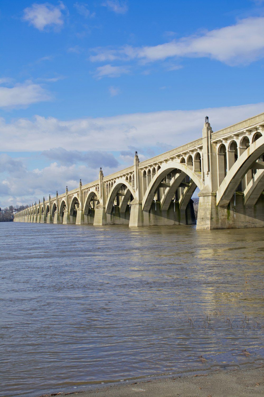 a bridge over a body of water under a cloudy blue sky