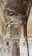 A richly detailed stone wall is adorned with intricate carvings and inscriptions. The arch design frames a section with abstract patterns and scripts, possibly of historical or religious significance. The stonework features varying shades and textures, contributing to a rustic yet majestic appearance.